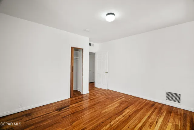 a view of a hallway with wooden floor and a bathroom