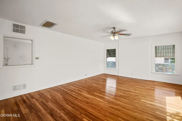 a view of an empty room with a window and wooden floor