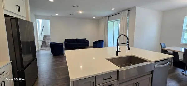 a kitchen with stainless steel appliances granite countertop a refrigerator a stove and a sink with wooden floor