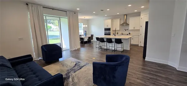 a living room with stainless steel appliances granite countertop furniture a couch a table and wooden floor