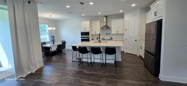 a kitchen with stainless steel appliances kitchen island granite countertop a refrigerator and a dining table