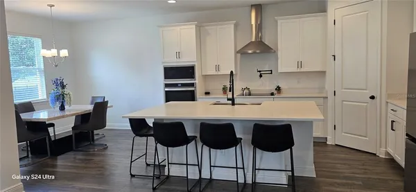 a kitchen with stainless steel appliances a dining table chairs and wooden floor