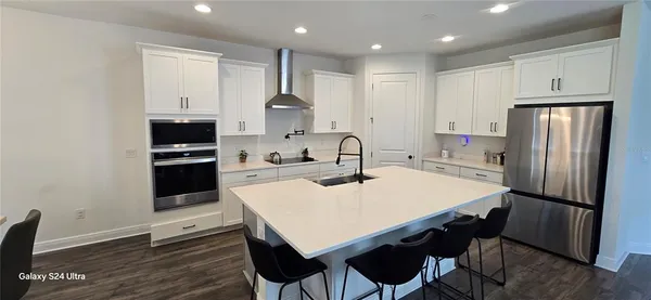 a kitchen with stainless steel appliances a table chairs refrigerator and microwave
