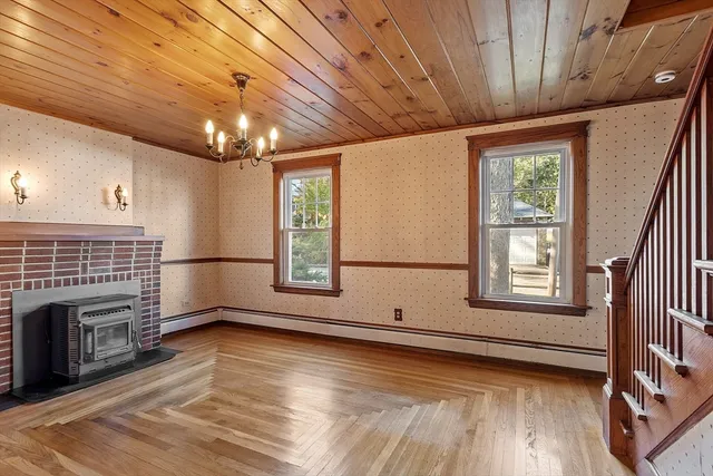a view of an empty room with wooden floor fireplace and a window