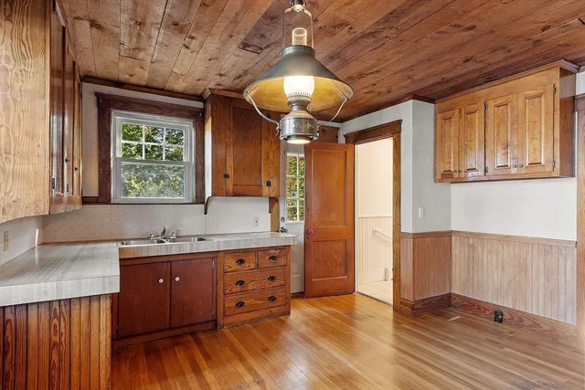 a kitchen with stainless steel appliances granite countertop a refrigerator a sink dishwasher a stove and white countertops with wooden floor