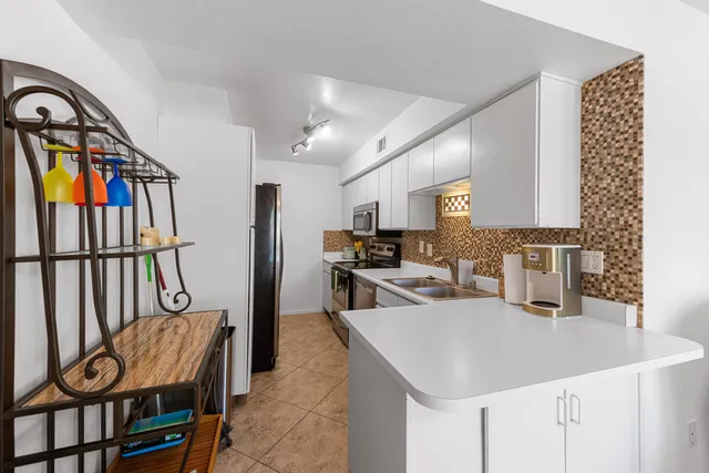 a kitchen with stainless steel appliances granite countertop a sink and a refrigerator