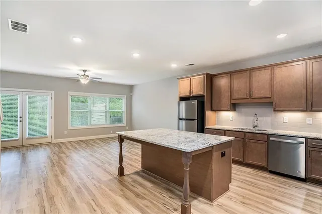 a large kitchen with kitchen island a sink dishwasher a stove and a refrigerator with wooden floor