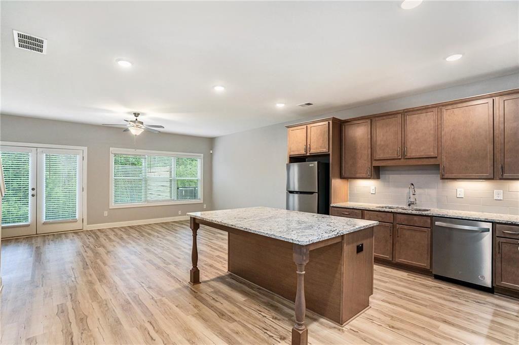 1341 Parc Bench Road Atlanta, GA 30316 - Photo 11 of 28 a large kitchen with kitchen island a sink dishwasher a stove and a refrigerator with wooden floor