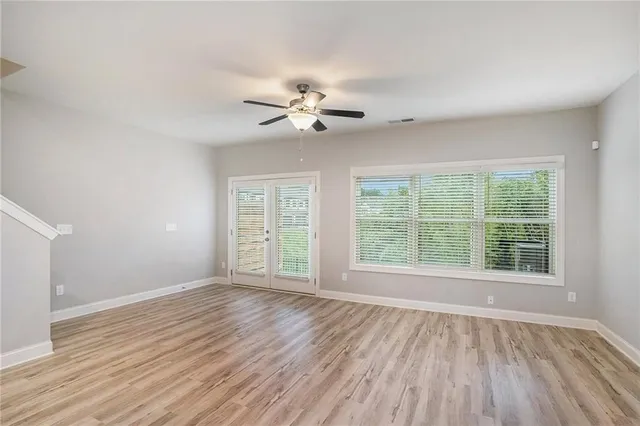 a view of an empty room with a window and wooden floor