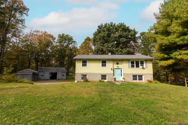 a front view of house with yard and trees in the background
