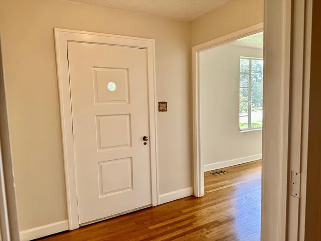 an empty room with wooden floor door and windows