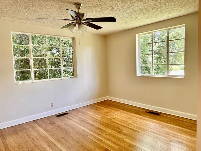 a view of an empty room with a window and wooden floor