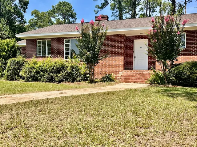 a front view of house with yard and trees around