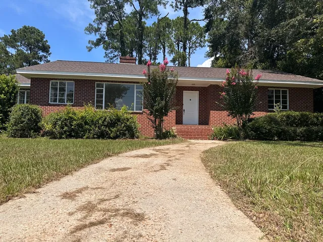 a front view of house with yard and trees around