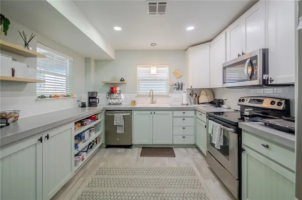 a kitchen with stainless steel appliances granite countertop a sink a stove and cabinets