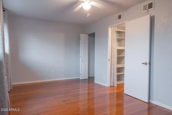 an empty room with wooden floor cabinet and windows