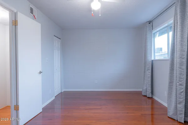 a view of an empty room with wooden floor and a window