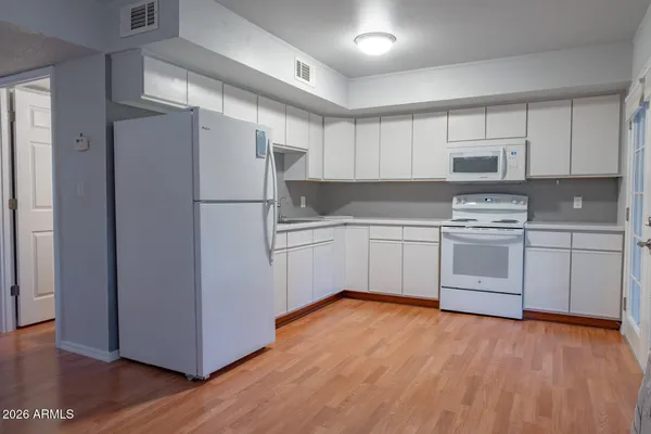 a kitchen with white cabinets and white appliances
