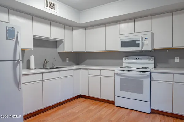 a kitchen with granite countertop white cabinets and white appliances