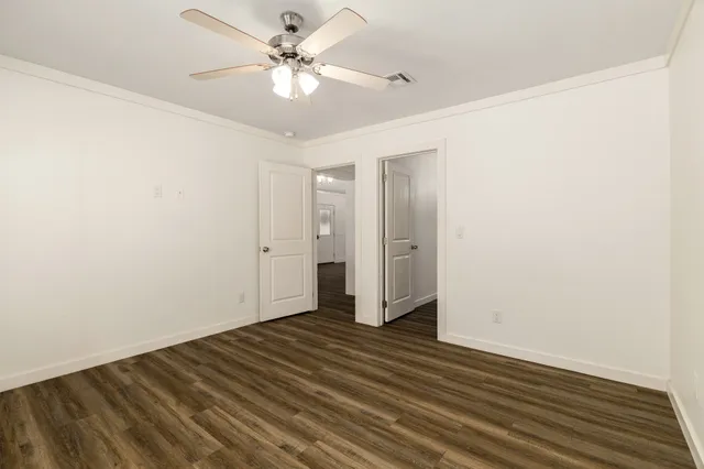 an empty room with wooden floor and fan