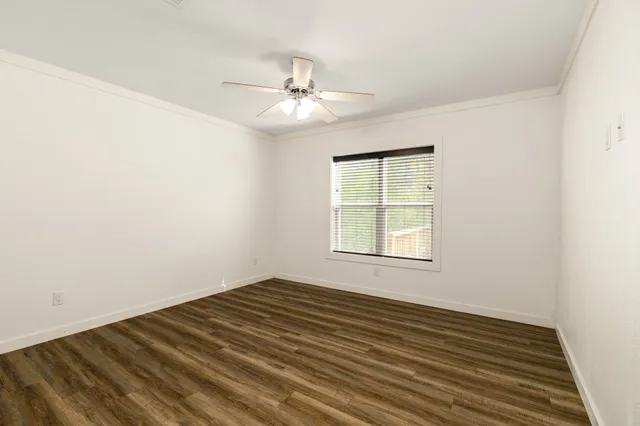 an empty room with wooden floor fan and windows