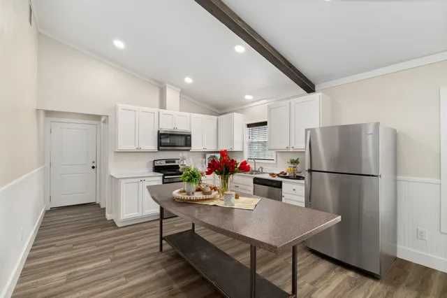 a kitchen with a refrigerator a white stove top oven a sink dishwasher and white cabinets with wooden floor