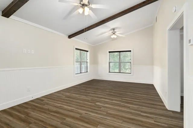 a view of an empty room with a window and wooden floor