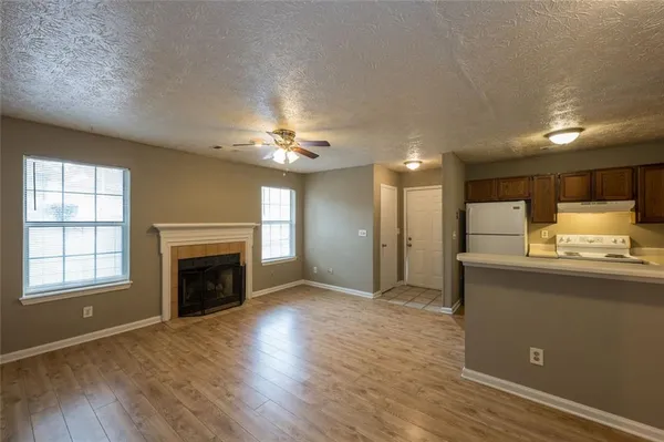 a view of kitchen and empty room with wooden floor and fireplace