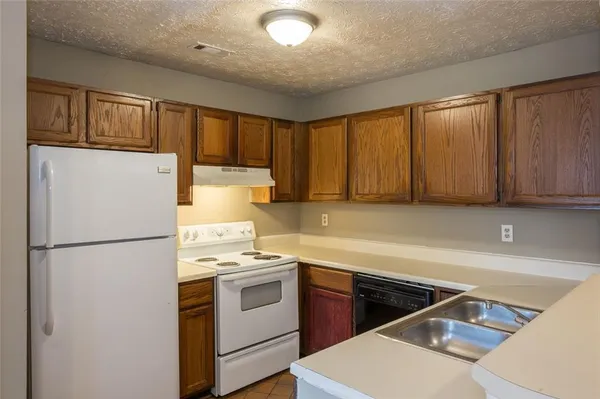 a kitchen with a refrigerator a stove top oven a sink and cabinets