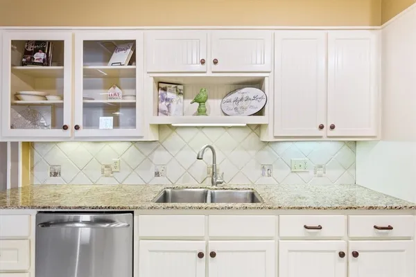 a kitchen with granite countertop white cabinets and a wooden floor