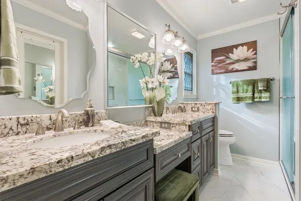 a bathroom with a granite countertop double vanity and a mirror