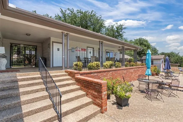 a front view of a house with plants and seating space