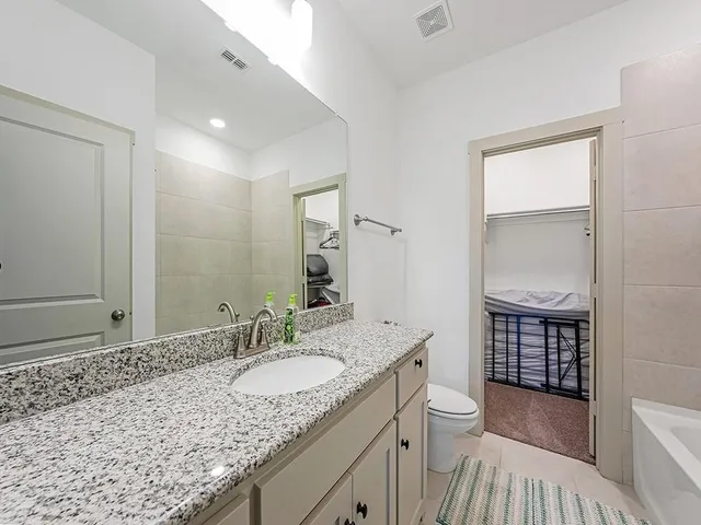 a bathroom with a granite countertop sink a toilet and shower