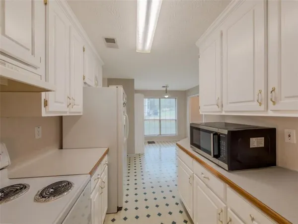 a kitchen with stainless steel appliances a refrigerator a stove and white cabinets