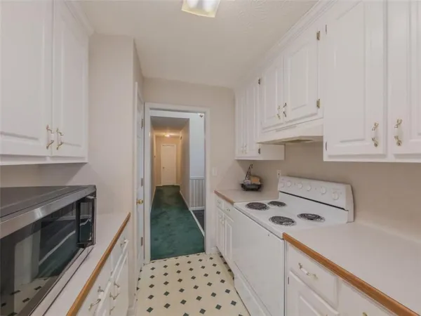 a kitchen with granite countertop a stove oven and white cabinets