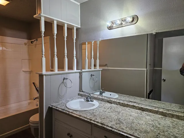 a bathroom with a granite countertop sink and a mirror