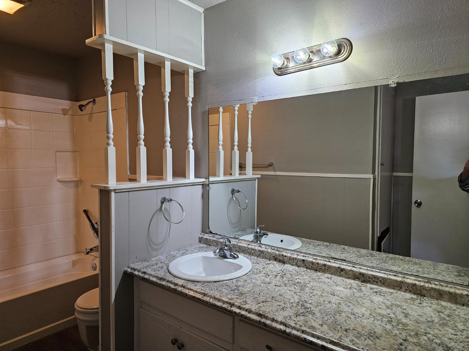 6501 Avenue R, Unit 6503 Lubbock, TX 79412 - Photo 9 of 11 a bathroom with a granite countertop sink and a mirror