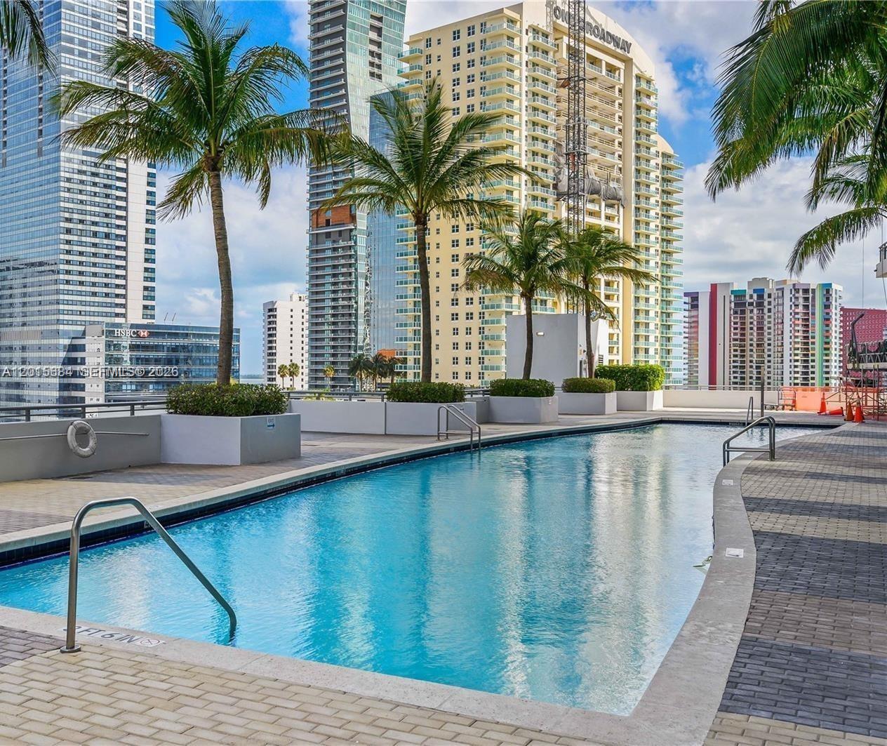 60 Southwest 13th Street, Unit 3609 Miami, FL 33130 - Photo 16 of 24 a view of a swimming pool with a chair and palm trees