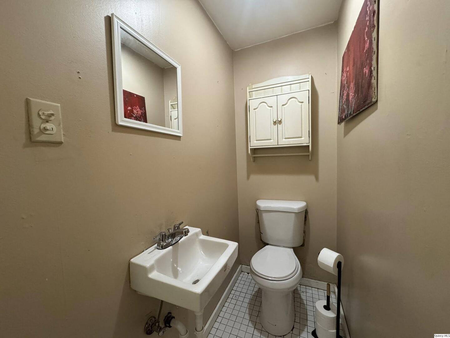 608 Adams Street Quincy, IL 62301 - Photo 7 of 19 a bathroom with a toilet sink and mirror