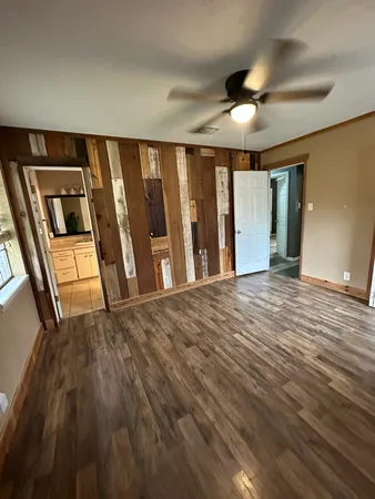 a view of an empty room with wooden floor and fan