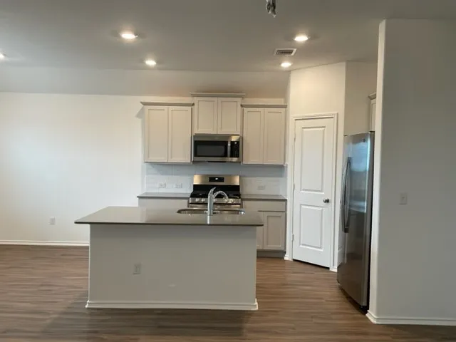 a kitchen with kitchen island a refrigerator sink and microwave