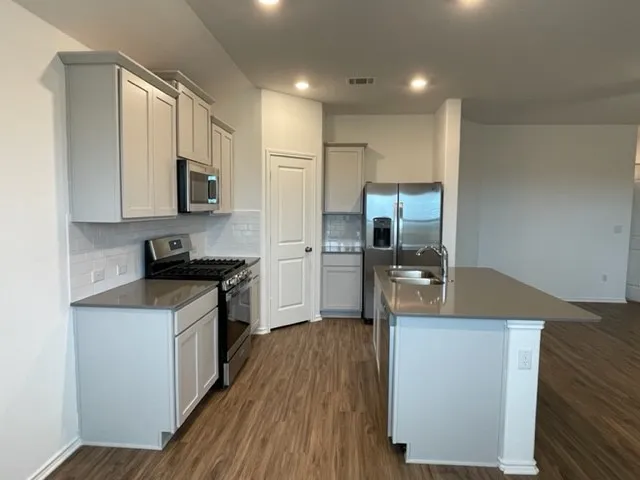 a kitchen that has a sink cabinets and wooden floor