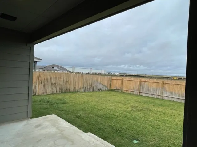a view of a backyard with grass & fence