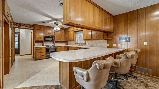 a kitchen with stainless steel appliances kitchen island granite countertop a table chairs in it and wooden floors