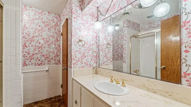 a bathroom with a granite countertop sink a mirror a shower and a vanity