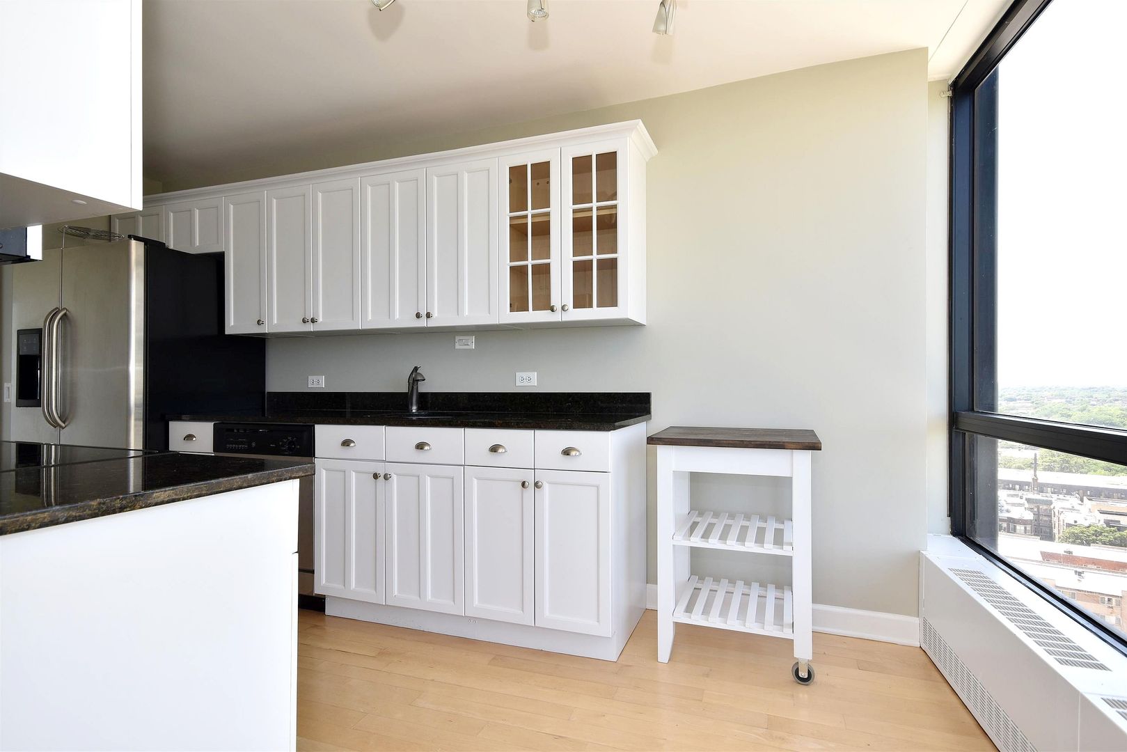 5415 North Sheridan Road, Unit 1806 Chicago, IL 60640 - Photo 12 of 38 a kitchen with granite countertop white cabinets and window