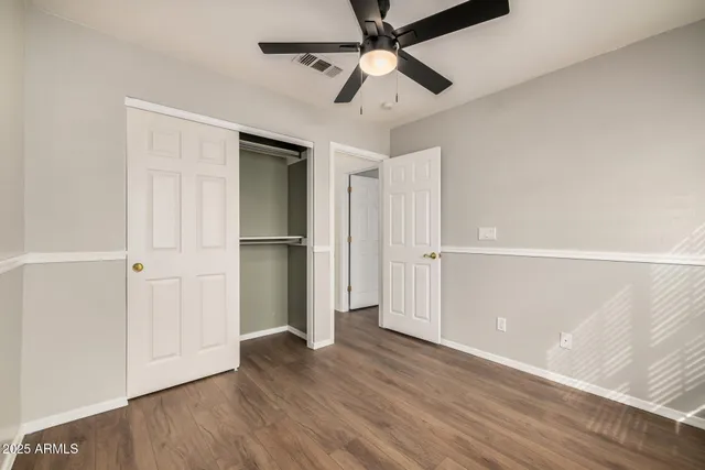 an empty room with wooden floor closet and windows