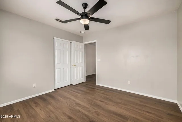an empty room with wooden floor and ceiling fan