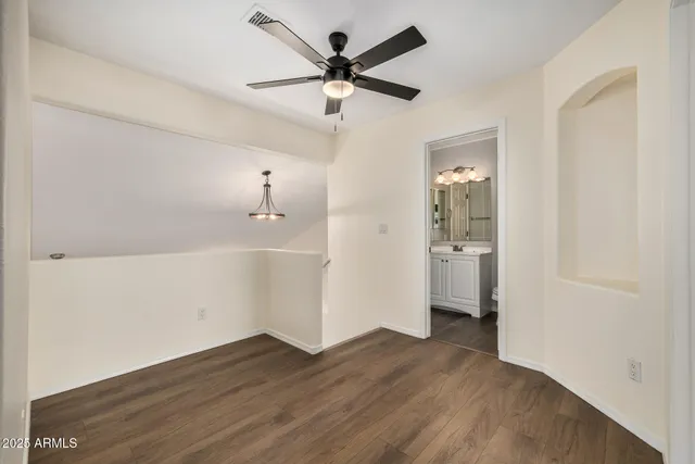 an empty room with wooden floor and a ceiling fan