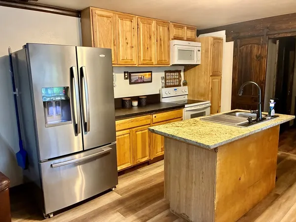a kitchen with stainless steel appliances granite countertop a refrigerator a stove and a sink with wooden floor